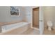 Bright bathroom features a soaking tub, tiled shower and floor, and neutral color palette at 943 Van Loon Ct, Kissimmee, FL 34758