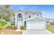 Charming two-story home with a two car garage, manicured landscaping, and a light blue exterior at 943 Van Loon Ct, Kissimmee, FL 34758