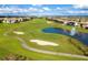 Aerial view of the community golf course featuring a lake with a fountain, sand traps, and well-maintained greens at 1048 Leader St, Davenport, FL 33896