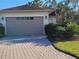 Charming single-story home featuring a paver driveway, tropical landscaping, and a neutral-tone garage door at 133 Indian Wells Ave, Kissimmee, FL 34759