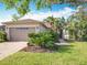 Beautiful one-story home with a manicured lawn, tropical plants, and a two-car garage at 133 Indian Wells Ave, Kissimmee, FL 34759