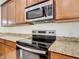 Close-up view of the kitchen featuring granite countertops and stainless steel appliances at 133 Indian Wells Ave, Kissimmee, FL 34759