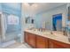 Blue themed bathroom with a double sink vanity and a shower-over-tub setup with a glass enclosure at 1686 Shadowmoss Cir, Lake Mary, FL 32746