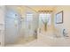 Bright bathroom featuring a glass-enclosed shower, soaking tub, and natural light from a decorative glass block window at 1686 Shadowmoss Cir, Lake Mary, FL 32746