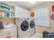 Modern laundry room featuring white cabinetry, sink, and front load washer and dryer, next to a shuttered window at 1686 Shadowmoss Cir, Lake Mary, FL 32746