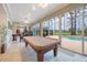 Large room with a pool table and an exterior view through the glass doors to the pool area and landscaping at 1686 Shadowmoss Cir, Lake Mary, FL 32746