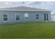 Rear exterior of the home with sliding glass doors, several windows and a large, green lawn at 1707 Ambar Ct, Winter Haven, FL 33881