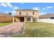 This backyard features a manicured lawn, covered patio, and brick-paved driveway at 2020 Windcrest Lake Cir, Orlando, FL 32824