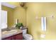 Cozy half-bath with a sink, toilet, large mirror, and towel rack in a cheerful yellow at 2020 Windcrest Lake Cir, Orlando, FL 32824