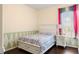 Bright bedroom featuring a floral comforter, a wood floor, and a window with colorful curtains at 2020 Windcrest Lake Cir, Orlando, FL 32824
