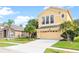 Charming two-story home with a spacious driveway and a manicured front lawn with mature palm trees at 2020 Windcrest Lake Cir, Orlando, FL 32824