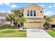 This two-story home has a well-maintained lawn, mature palm trees, and neutral colored stucco at 2020 Windcrest Lake Cir, Orlando, FL 32824