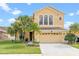 Stunning home with a well-manicured lawn, palm trees, and a spacious driveway leading to the garage at 2020 Windcrest Lake Cir, Orlando, FL 32824