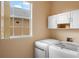 Laundry room featuring a front load washer and dryer, white cabinets and a window at 2020 Windcrest Lake Cir, Orlando, FL 32824
