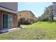 Grassy backyard, view of townhome exteriors, and a sliding glass door entry to the home at 2120 Betsy Ross Ln, St Cloud, FL 34769