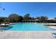 A stunning community pool with surrounding lounge areas under a clear sky on a sunny day at 2120 Betsy Ross Ln, St Cloud, FL 34769
