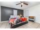 Cozy bedroom featuring a ceiling fan, neutral-toned tile floor, a stylish quilt, and a dark accent wall at 2237 Avenue B Nw, Winter Haven, FL 33880