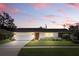 Charming single-story home featuring a well-manicured lawn and a freshly painted white brick facade under a colorful sky at 2654 Derbyshire Rd, Maitland, FL 32751
