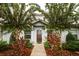 Inviting townhome entrance with a brown front door, complemented by lush landscaping and mature trees at 2962 Lucayan Harbour Cir # 102, Kissimmee, FL 34746