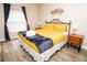 A bedroom with a wrought iron bed frame, yellow bedding, wood nightstands, and decorative wall art at 2962 Lucayan Harbour Cir # 102, Kissimmee, FL 34746