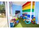 Colorful playroom with toys, artificial turf, and a rainbow-striped accent wall at 2962 Lucayan Harbour Cir # 102, Kissimmee, FL 34746