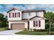 Charming two-story home with a well-manicured lawn, attached garage, and vibrant red shutters at 5453 Catmint Dr, Lake Hamilton, FL 33851