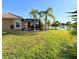 Backyard view with a screened lanai, tropical landscaping, and lake access at 551 San Raphael St, Kissimmee, FL 34759