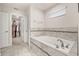 Relax and unwind in this bath featuring tiled surround, natural light, and easy access to walk-in closet at 5685 Surprise Lily Dr, Winter Garden, FL 34787