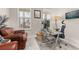 Bright home office with two windows, a glass desk, and comfortable seating area at 5685 Surprise Lily Dr, Winter Garden, FL 34787