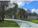 Charming single-story home with a long driveway, white brick, and a columned front porch on a sunny day at 616 N Palm Ave, Kissimmee, FL 34741