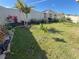 Backyard featuring green grass, flowering plants, and young trees at 676 Tanaro Ln, Haines City, FL 33844