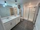 Modern bathroom with dual sinks, white cabinets, and a glass-enclosed shower at 676 Tanaro Ln, Haines City, FL 33844