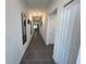Long, bright hallway featuring modern tile flooring, white walls, and stylish light fixtures at 676 Tanaro Ln, Haines City, FL 33844