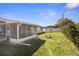 Backyard featuring green grass, a bench, screened in porch, and perimeter landscaping at 706 Francis St, Kissimmee, FL 34741