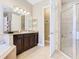 Well-lit bathroom featuring a double sink, granite countertop, bathtub, and glass shower, with neutral tile flooring at 741 Villa Park Rd, Poinciana, FL 34759