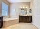 Bathroom featuring a soaking tub, granite countertop vanity, and a large mirror with lighting at 741 Villa Park Rd, Poinciana, FL 34759