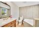 Bathroom with a decorative mirror, wood vanity, tub, and light gray tiling at 78 N 5Th St, Orlando, FL 32833