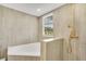Bathroom with a tub, shower with golden shower head, window, and light gray tiling at 78 N 5Th St, Orlando, FL 32833