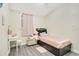 A serene bedroom featuring a single bed, a vanity, and a window with sheer pink curtains, creating a peaceful ambiance at 78 N 5Th St, Orlando, FL 32833