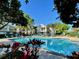 Community pool surrounded by lush landscaping and comfortable lounge chairs under a clear blue sky at 8300 Elm Park Dr # 7110, Orlando, FL 32821