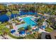 Aerial view of a community pool surrounded by palm trees, lounge chairs, and a serene lake at 8300 Portofino Dr # 403, Davenport, FL 33896