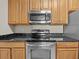 Kitchen with stainless steel microwave, oven, wood cabinets, and granite countertops at 8300 Portofino Dr # 403, Davenport, FL 33896