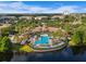 Aerial view of resort-style community pool surrounded by lush landscaping and lounge seating near a lake at 8300 Portofino Dr # 403, Davenport, FL 33896