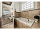 Bright bathroom with a tub, neutral tile, and a window providing natural light at 861 Golden Bear Dr, Reunion, FL 34747