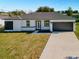 Charming single-story home with a well-manicured lawn and a dark grey, two-car garage door at 10 Dogwood Loop Ave, Ocala, FL 34472