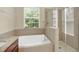 Bright bathroom featuring a soaking tub, a glass-enclosed shower, neutral tile, and vanity with granite countertop at 1000 Seburn Rd, Apopka, FL 32703