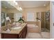 Bright bathroom featuring a double vanity with granite countertops, a bathtub, and a glass-enclosed shower at 1000 Seburn Rd, Apopka, FL 32703