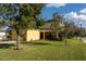 View of the yellow home with a manicured lawn and large shade trees at 1000 Seburn Rd, Apopka, FL 32703