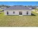 Rear exterior view of home with a sliding door, windows, and large backyard at 110 Alta Vista Way, Davenport, FL 33837