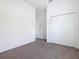 Bright bedroom with neutral carpet, double-door closet, and a view into the next room at 110 Alta Vista Way, Davenport, FL 33837